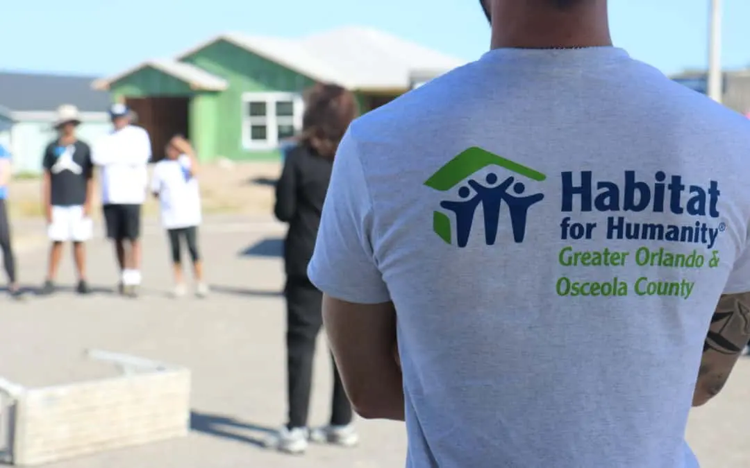 Um voluntário com uma camiseta da Habitat Orlando &amp; Osceola olha para um canteiro de obras.