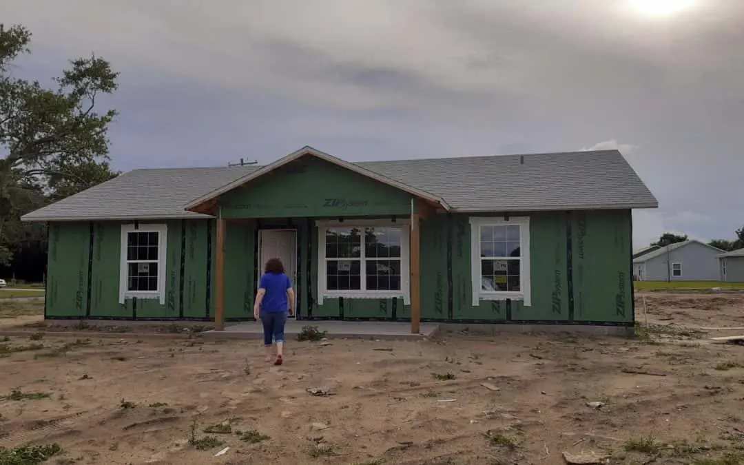 woman walks towards her in-progress house