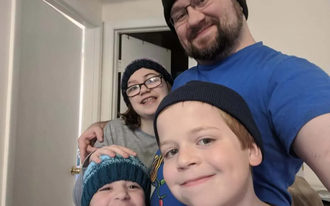 A father poses for a photo with his three children.