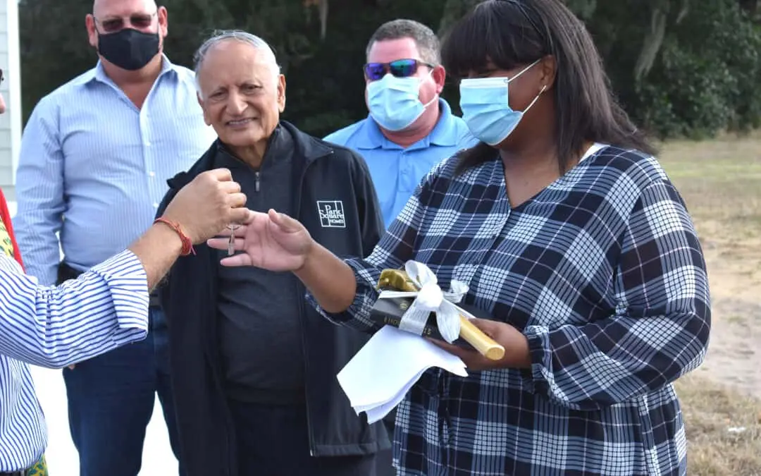 A woman receives her house keys as other watch.