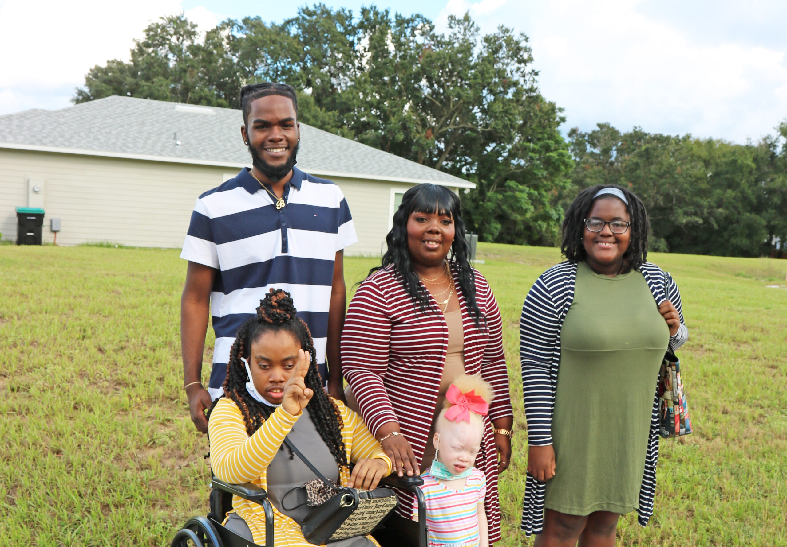 Shuprina and family Five people smile at the camera in front of future habitat home